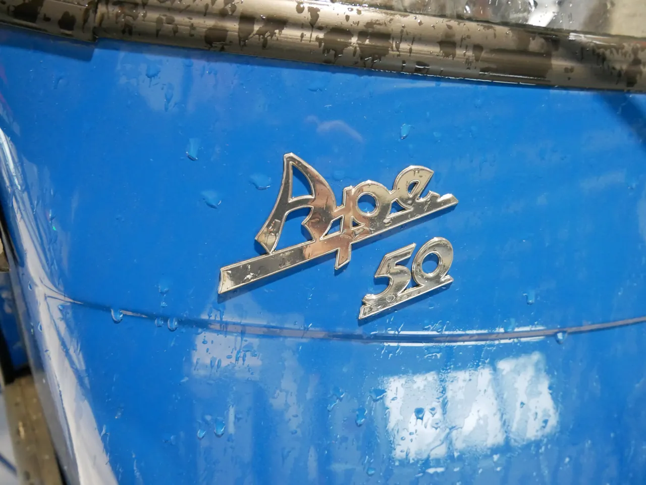 Piaggio Ape 50 – Ape-50-Schriftzug an der Fronthaube der Fahrerkabine, Detailaufnahme bei der Besichtigung