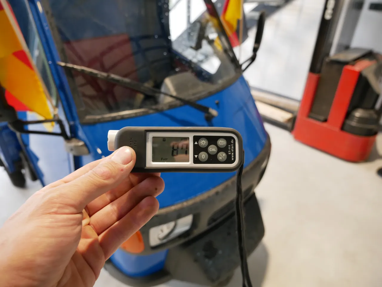 Lackschichtdickenmessung am Piaggio Ape 50 – Messgerät bei der Aufnahme der Lackstärke in der Halle